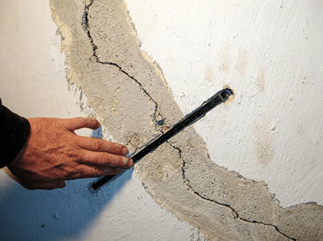 A wall with a large crack is being inspected by a professional in Stamford, CT